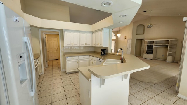 kitchen featuring a breakfast bar, sink, white cabinets, kitchen peninsula, and white appliances