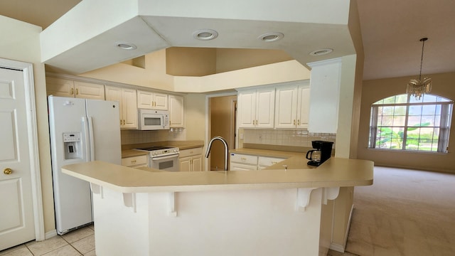 kitchen with decorative backsplash, kitchen peninsula, white appliances, and light tile patterned floors