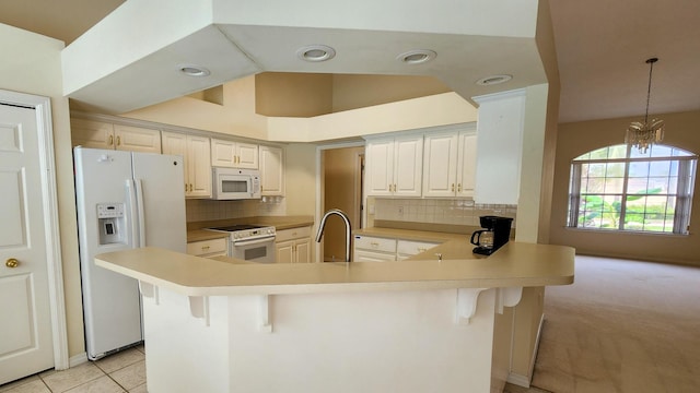 kitchen with white appliances, a breakfast bar, decorative backsplash, vaulted ceiling, and kitchen peninsula