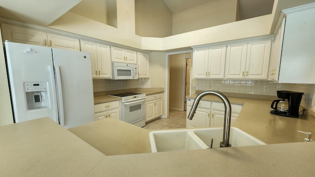 kitchen with tasteful backsplash, white appliances, light tile patterned floors, white cabinets, and a towering ceiling