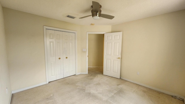 unfurnished bedroom featuring light colored carpet, a textured ceiling, ceiling fan, and a closet