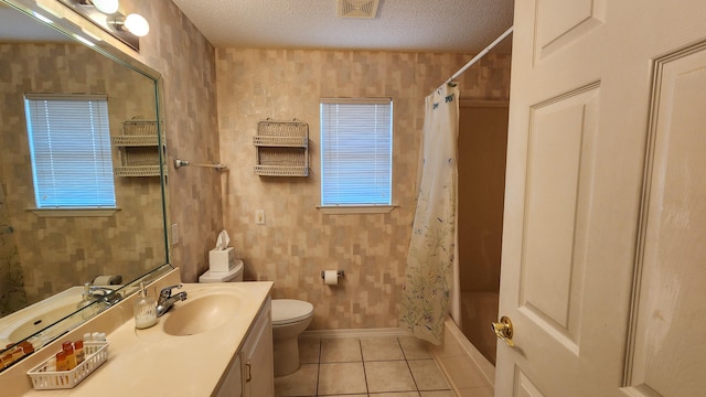 full bathroom featuring tile patterned flooring, a textured ceiling, toilet, vanity, and shower / tub combo with curtain