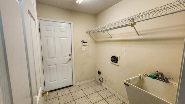 laundry area with sink, electric dryer hookup, hookup for a washing machine, a textured ceiling, and light tile patterned floors