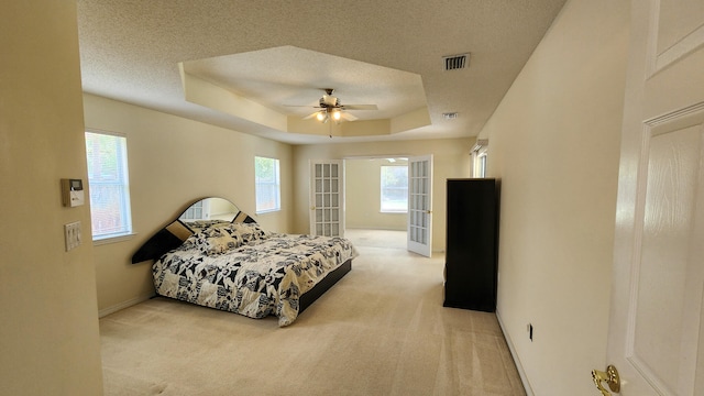 carpeted bedroom featuring ceiling fan, a textured ceiling, and a tray ceiling