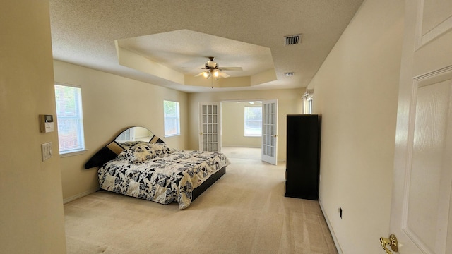 carpeted bedroom featuring french doors, ceiling fan, a raised ceiling, and a textured ceiling