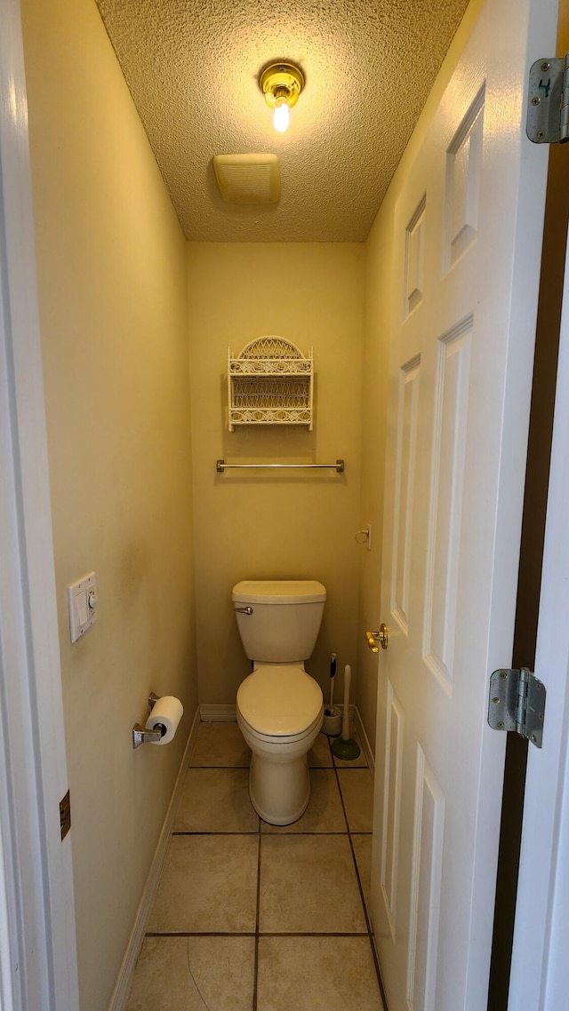 bathroom with tile patterned floors, toilet, and a textured ceiling