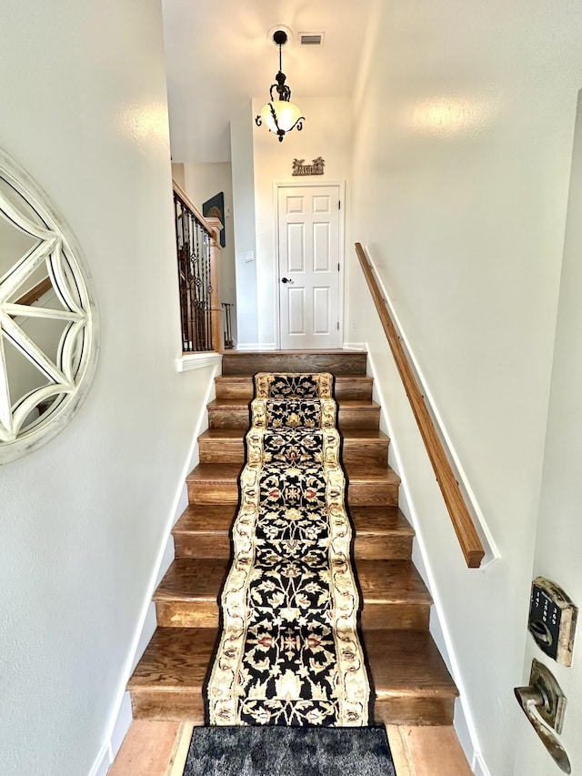 staircase featuring visible vents, baseboards, and wood finished floors