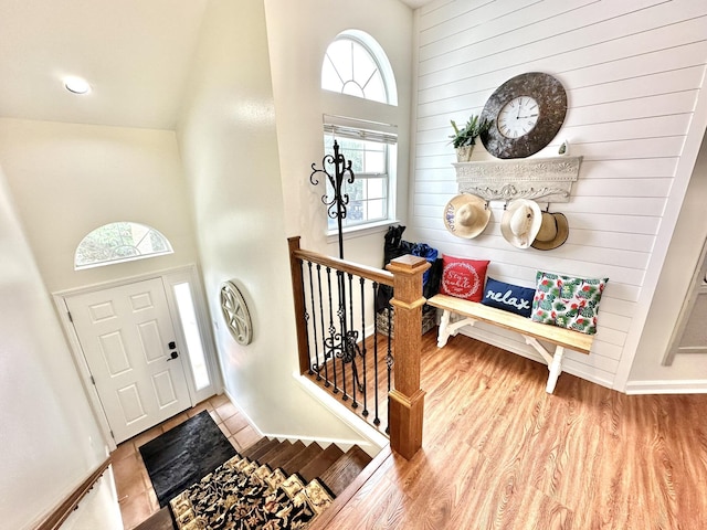 entryway with wood walls, a high ceiling, and wood finished floors