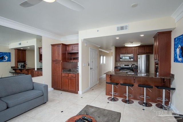 kitchen featuring light tile patterned floors, ornamental molding, appliances with stainless steel finishes, kitchen peninsula, and backsplash