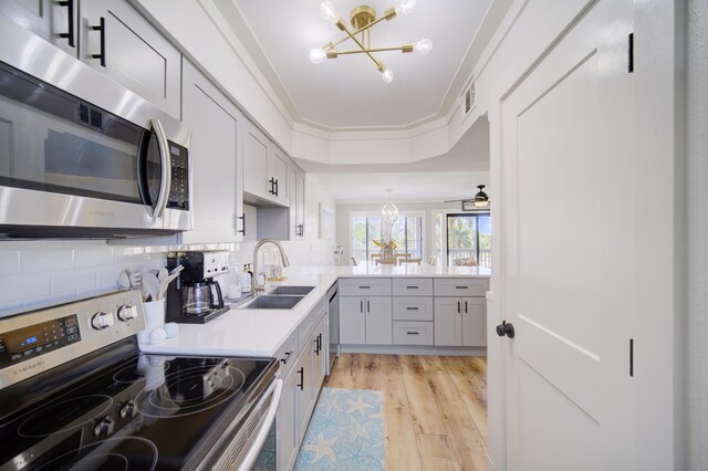 kitchen with stainless steel appliances, crown molding, light hardwood / wood-style floors, tasteful backsplash, and sink