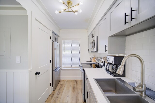 kitchen with tasteful backsplash, crown molding, stainless steel appliances, light hardwood / wood-style floors, and sink