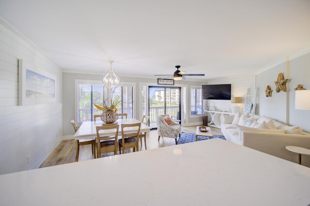 dining area with ceiling fan with notable chandelier, crown molding, and hardwood / wood-style floors