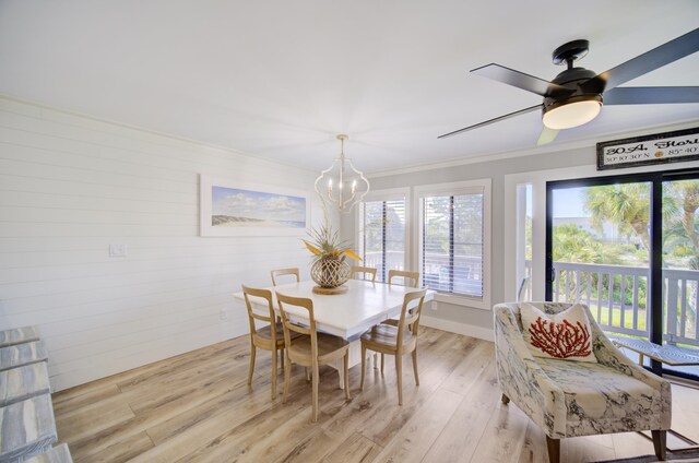 dining space featuring light wood-type flooring, ceiling fan with notable chandelier, and crown molding