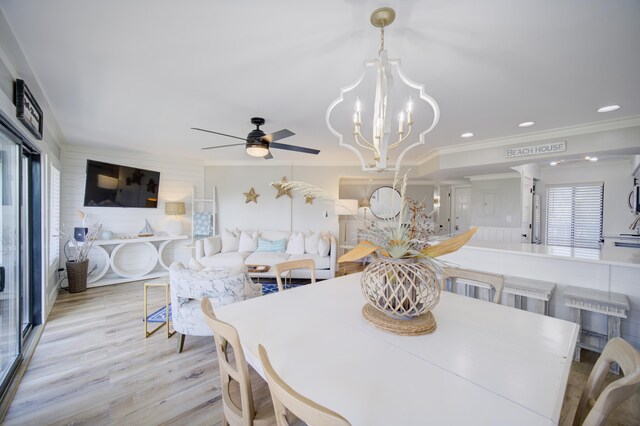 dining room with ceiling fan with notable chandelier, crown molding, and light hardwood / wood-style floors