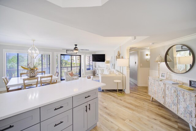 kitchen with gray cabinetry, ceiling fan with notable chandelier, a wealth of natural light, and light hardwood / wood-style floors