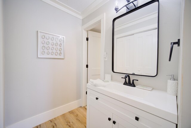 bathroom with ornamental molding, vanity, and hardwood / wood-style floors