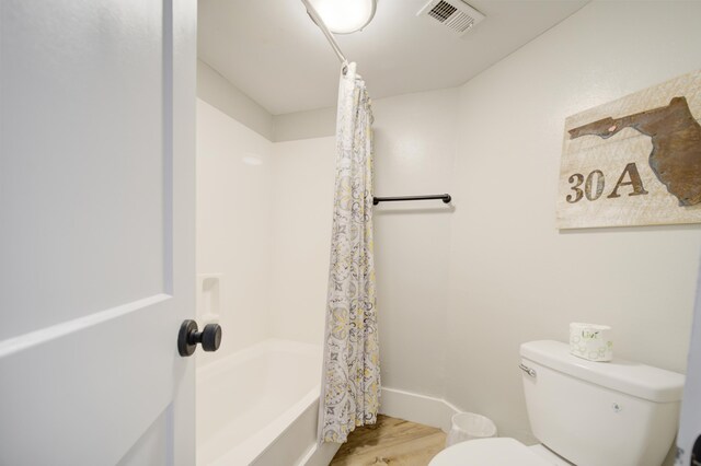 bathroom with shower / tub combo, toilet, and hardwood / wood-style floors