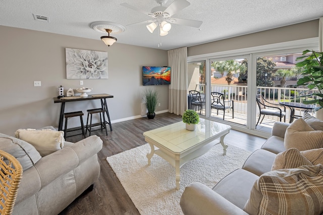 living room featuring dark wood-type flooring, visible vents, and a textured ceiling