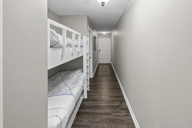 bedroom with a textured ceiling, dark wood finished floors, and baseboards