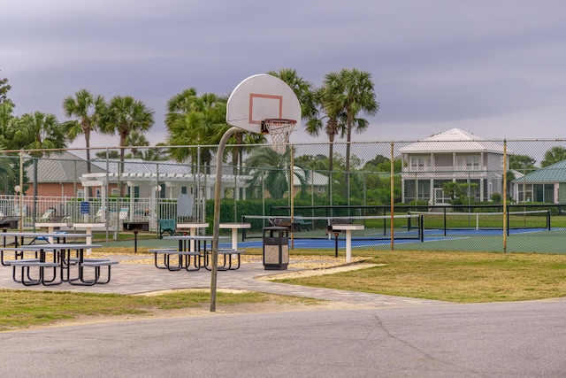 view of property's community with a tennis court, community basketball court, and fence