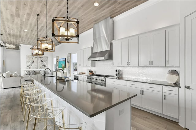 kitchen with pendant lighting, a kitchen bar, double oven range, and wall chimney range hood