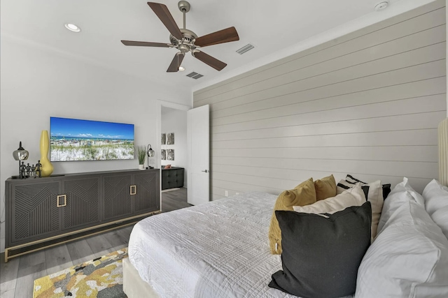 bedroom featuring dark hardwood / wood-style floors, ceiling fan, and wood walls