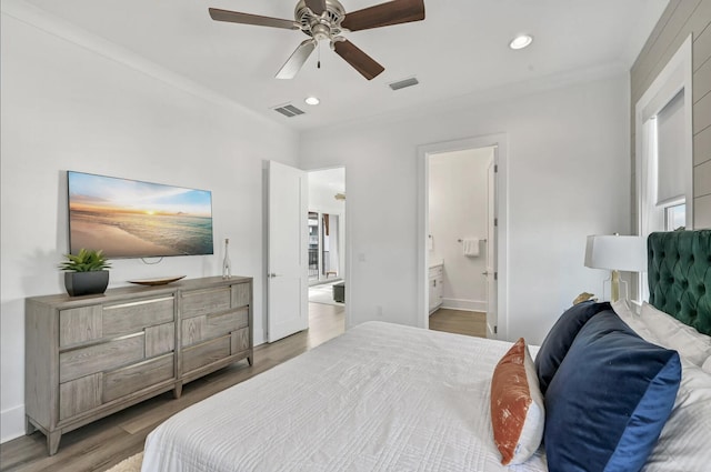 bedroom featuring hardwood / wood-style flooring, ceiling fan, ensuite bathroom, and crown molding