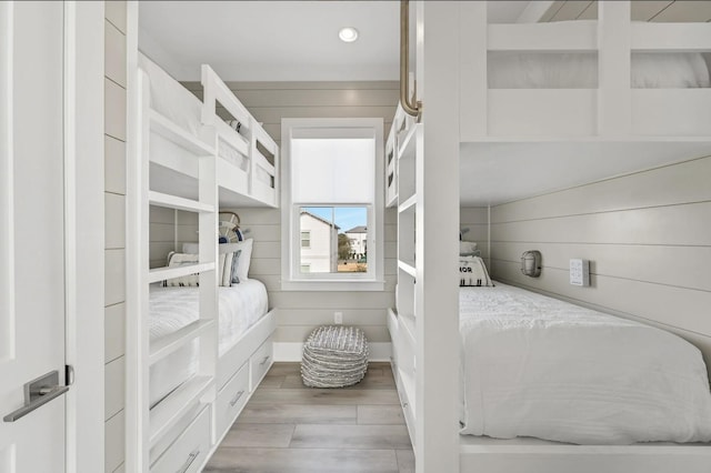 bedroom with wood walls and light hardwood / wood-style flooring