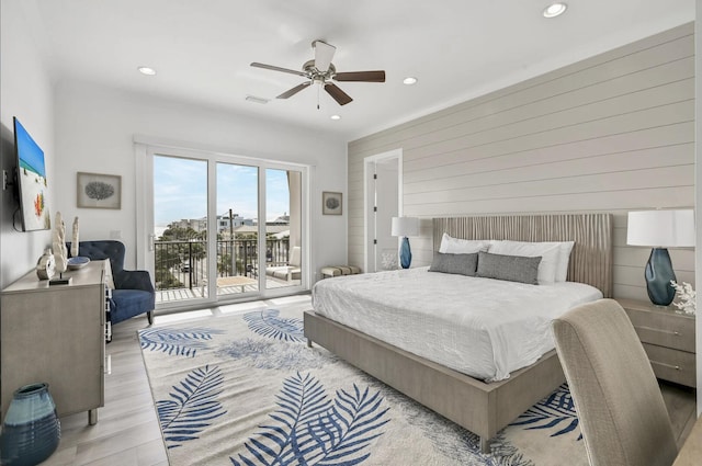 bedroom featuring wood walls, access to exterior, ceiling fan, and light hardwood / wood-style flooring