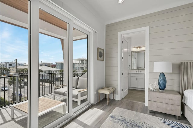 bedroom featuring wood walls, connected bathroom, light hardwood / wood-style floors, and access to outside