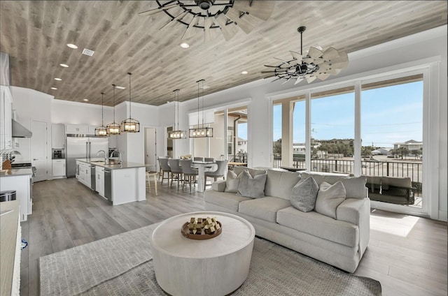 living room featuring ceiling fan with notable chandelier, wood ceiling, and light hardwood / wood-style flooring