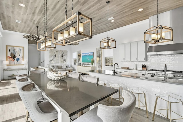 dining room featuring sink, wood ceiling, and light hardwood / wood-style flooring