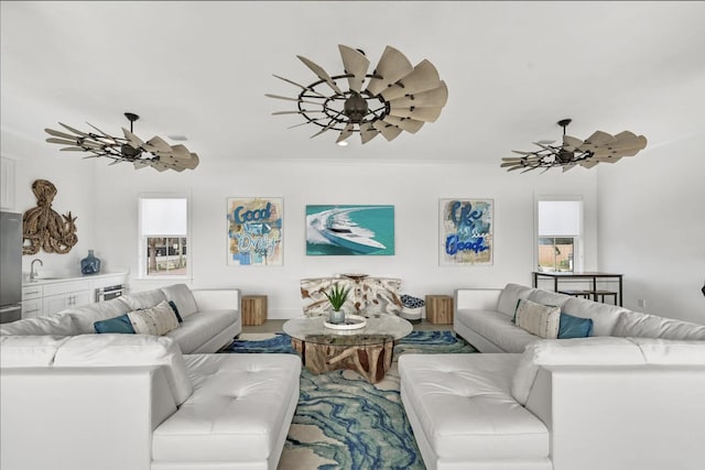 living room featuring ornamental molding, sink, and ceiling fan