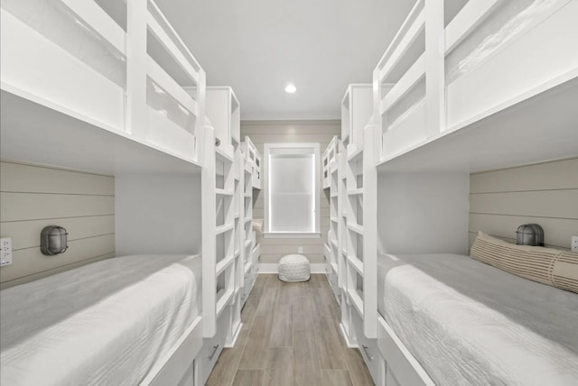 bedroom with wooden walls and light wood-type flooring