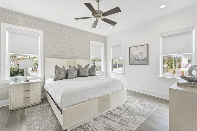 bedroom featuring dark hardwood / wood-style floors, ceiling fan, and wood walls