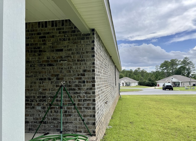 view of property exterior featuring brick siding, a yard, and stucco siding