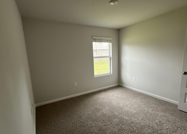 carpeted spare room featuring baseboards