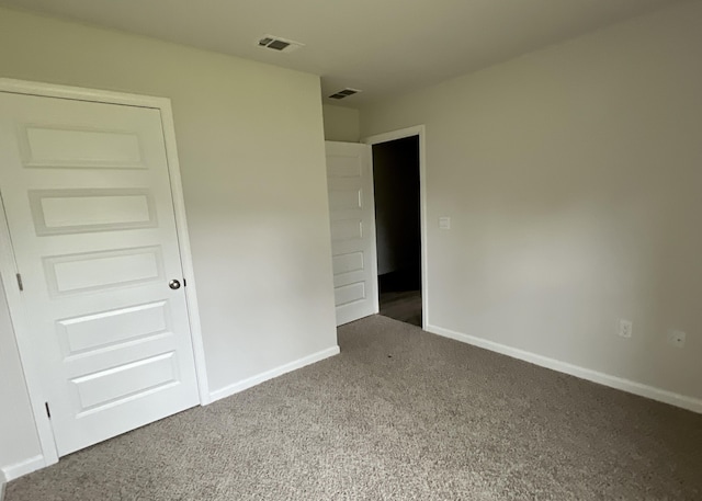 empty room with visible vents, dark carpet, and baseboards