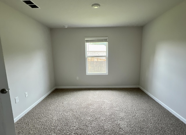 unfurnished room with carpet, visible vents, and baseboards