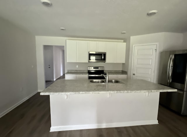 kitchen featuring a center island with sink, white cabinets, appliances with stainless steel finishes, dark wood-style flooring, and a sink