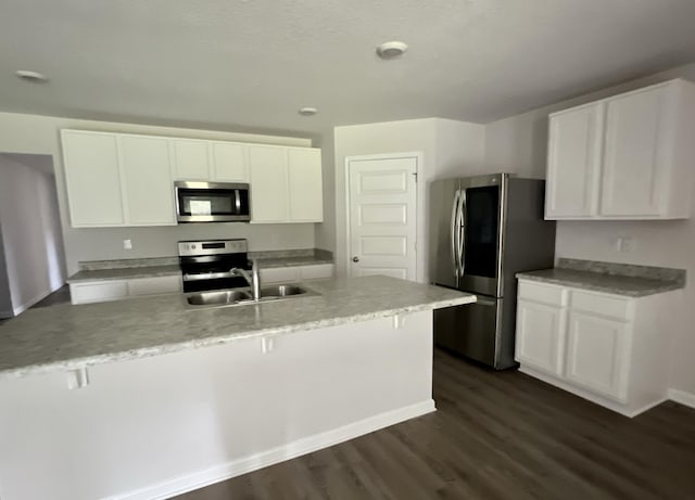 kitchen featuring dark wood finished floors, light countertops, appliances with stainless steel finishes, white cabinets, and a sink