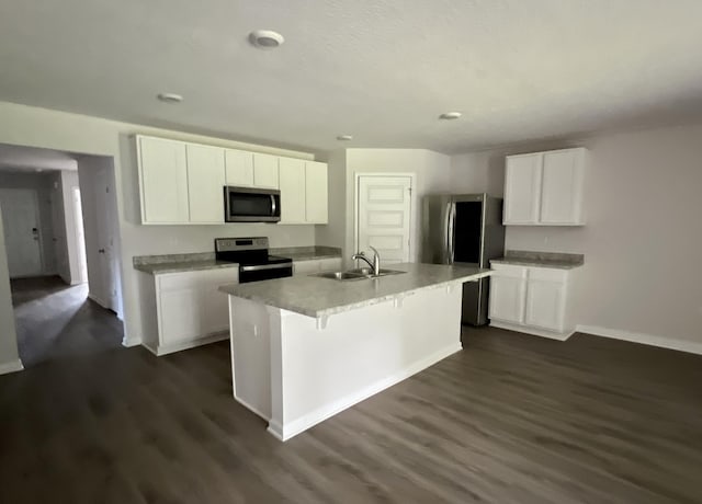 kitchen featuring a kitchen island with sink, stainless steel appliances, a sink, white cabinets, and light countertops