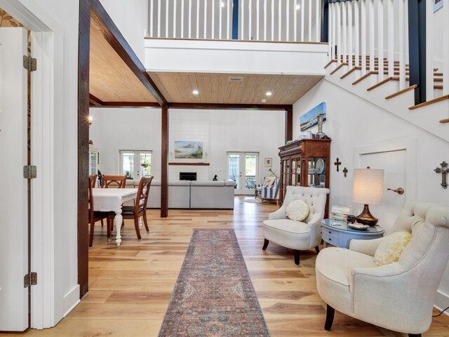 entrance foyer with a high ceiling, light hardwood / wood-style floors, wooden ceiling, french doors, and beamed ceiling