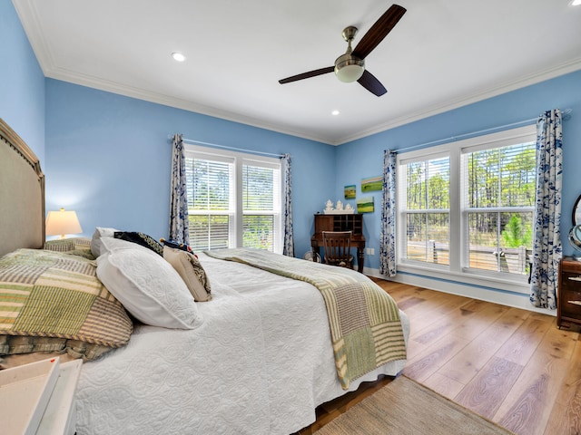 bedroom featuring ornamental molding, multiple windows, hardwood / wood-style flooring, and ceiling fan