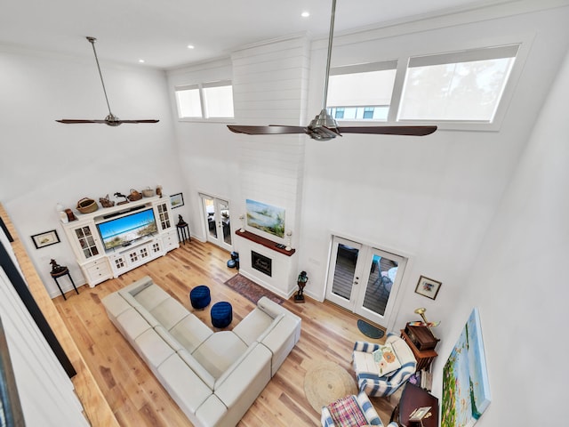 living room with a high ceiling, light wood-type flooring, and ceiling fan