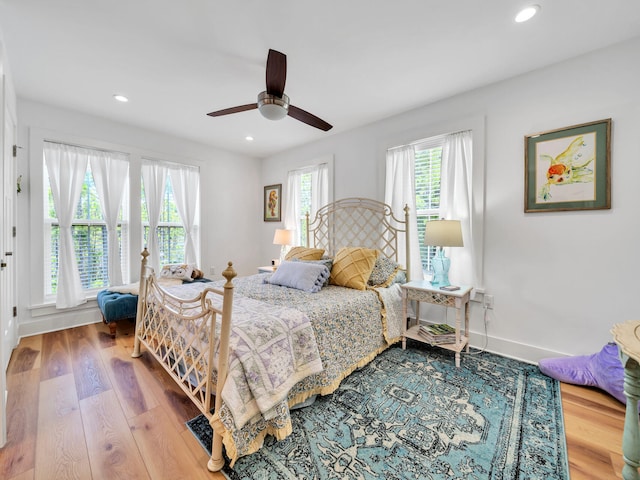 bedroom featuring multiple windows, ceiling fan, and light wood-type flooring