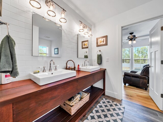 bathroom with tasteful backsplash, ceiling fan, tile walls, dual vanity, and wood-type flooring