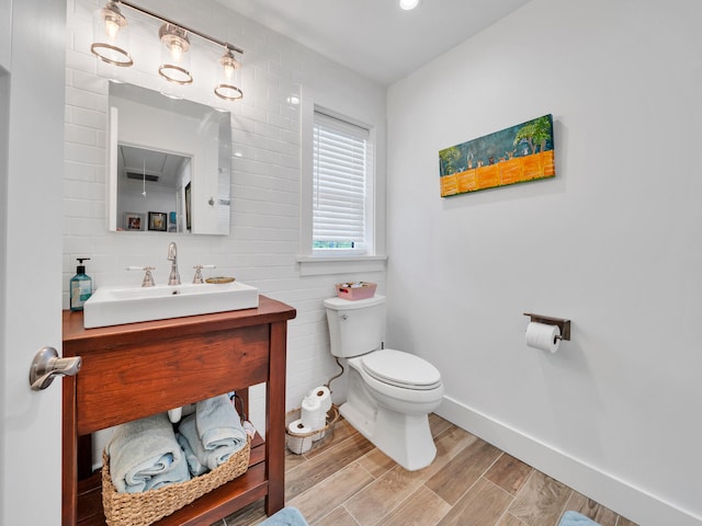 bathroom featuring hardwood / wood-style flooring, tile walls, toilet, and vanity