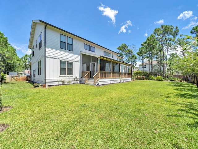 rear view of house featuring a sunroom and a lawn