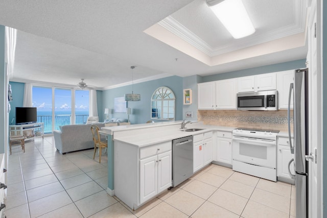 kitchen with kitchen peninsula, stainless steel appliances, ornamental molding, and white cabinets